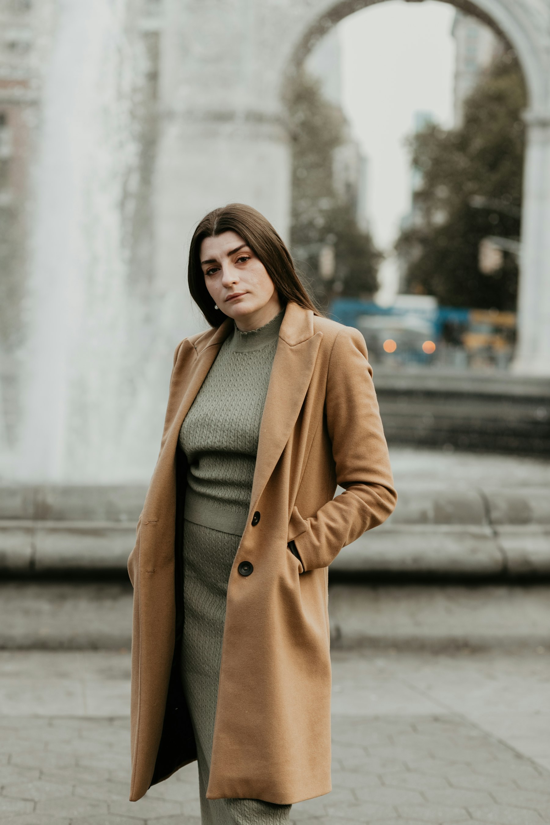 Şehir meydanında uzun kamel yün palto giyen kadın — temsili görsel